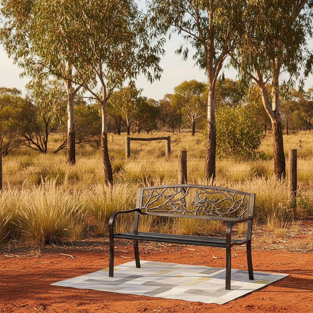 Decorative metal bench with bird and branch design on a patio