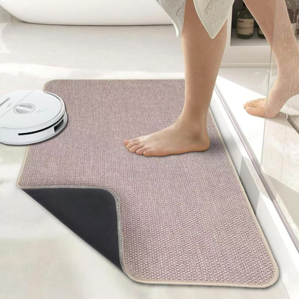 Person stepping onto a mat with a robot vacuum cleaner on the floor.